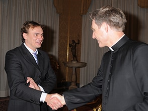 Andreas Englisch schüttelt einem Priester die Hand.