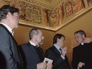 Andreas Englisch im Gespräch mit einem Priester und zwei weiteren Anzugträgern.