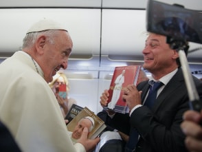 Andreas Englisch präsentiert Papst Franziskus lachend seine Bücher, während der Zweiterer bereits zwei in der Hand hält.