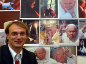 Andreas Englisch vor verschiedenen Bildern von Johannes Paul II.