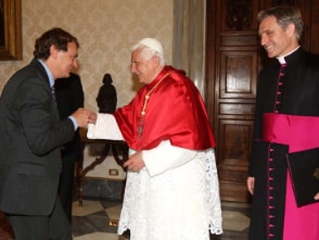 Andreas Englisch und Papst Benedikt XVI begrüßen sich, während auf der rechten Seite ein Kardinal lächeln zuschaut.